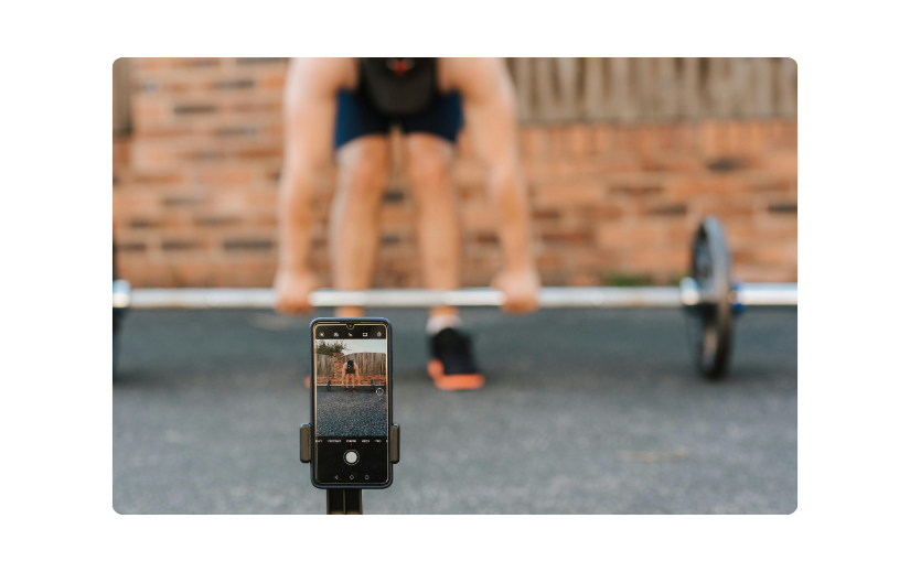 Smartphone grabando una sesión de entrenamiento, mostrando videos sin rostro como una estrategia para crear contenido atractivo de fitness.
